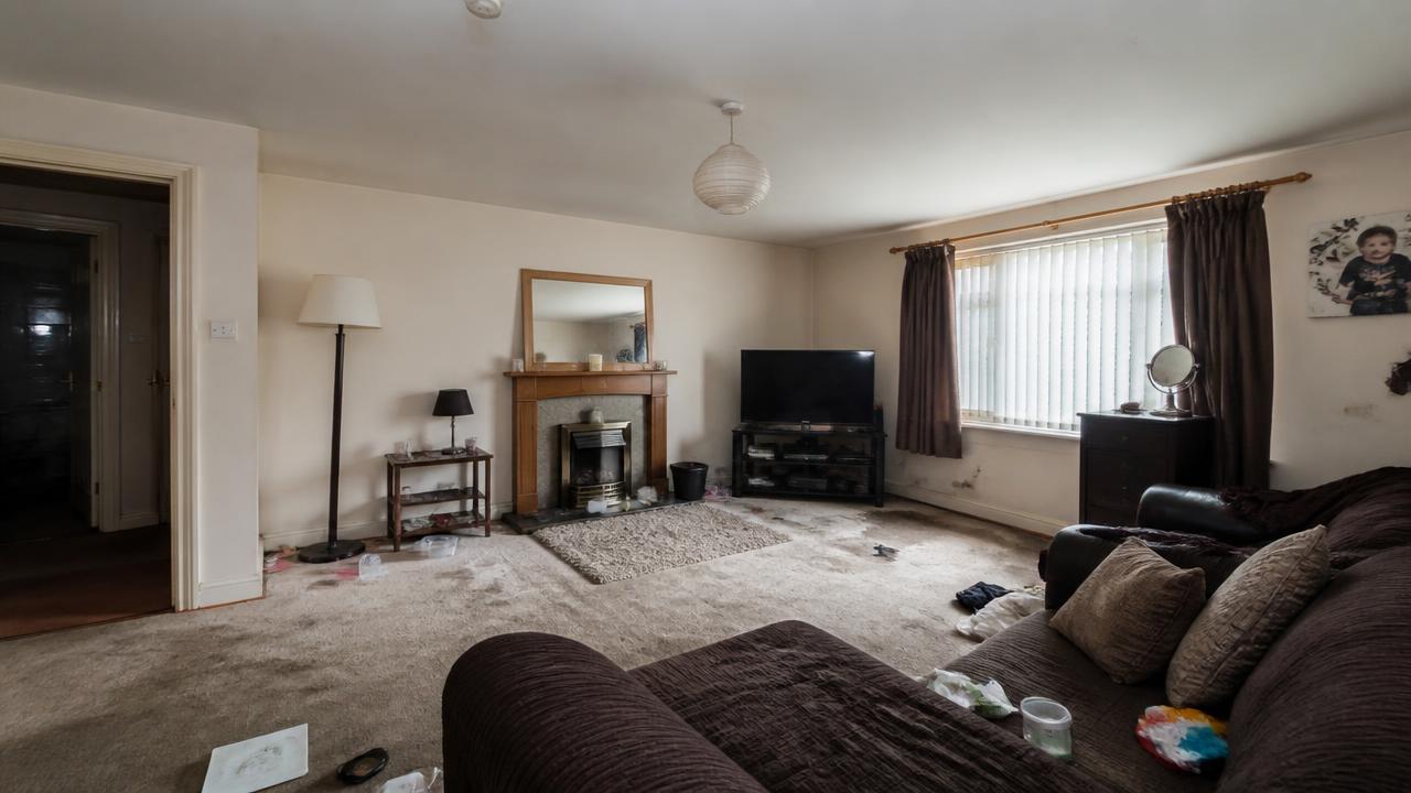 Living room before cleaning — stained carpet and scattered clutter